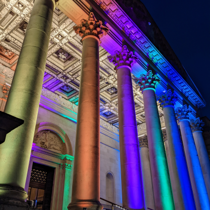 A highlight image for The front of the Fitzwilliam Museum at night illuminated with rainbow lights